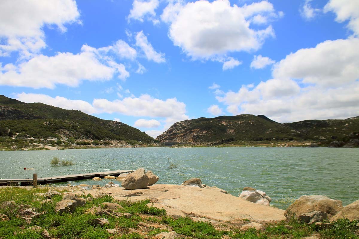 Lake Morena with a dock and backcountry hills under a blue sky