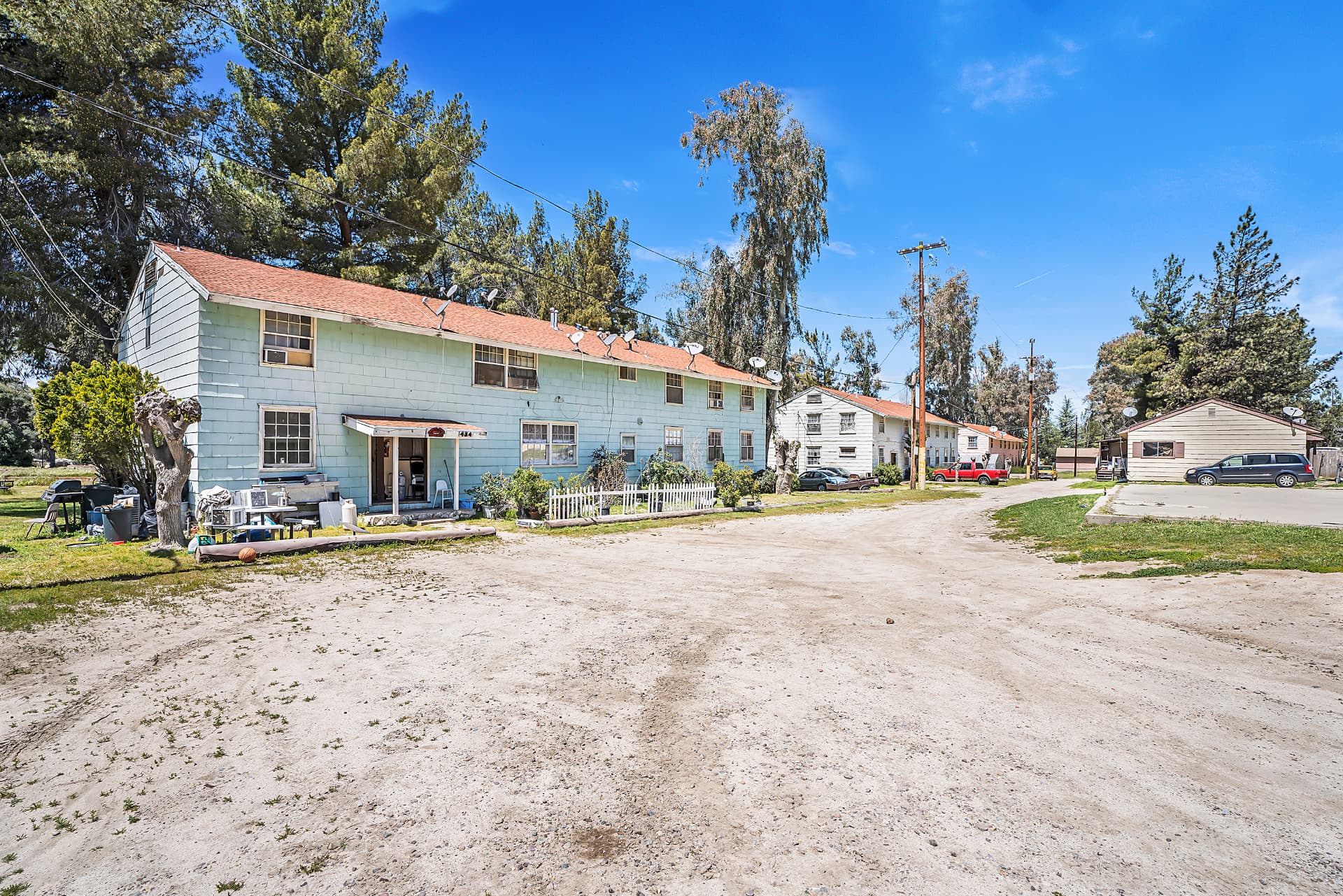 Two-story converted barracks apartments along a dirt lane